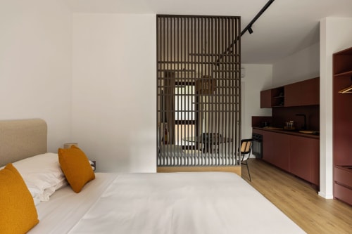 Camera da letto moderna all'appartamento Dimora Silva 3 con letto, cuscini arancioni, scrivania in legno, mobili in legno scuro e soffitto a listelli