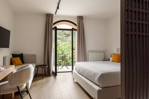 Luminosa camera da letto a Dimora Silva con porta ad arco che affaccia sul balcone di montagna, letti gemelli, scrivania e comfort moderni