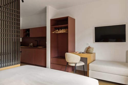 Monolocale moderno a Dimora Silva con angolo cottura bordeaux, area di lavoro, TV, divano e arredi in legno a San Martino