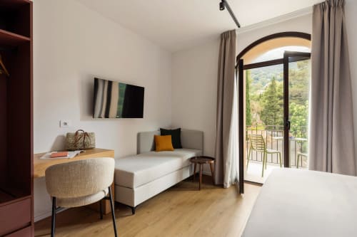 Camera moderna con vista montagna, divano, scrivania e porta-finestra arcata a Dimora Silva Nature Suites