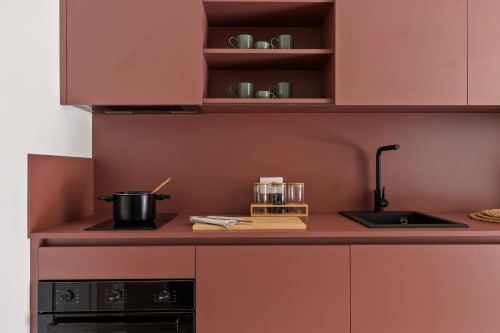 Cucina moderna nell'appartamento Dimora Silva 3 con mobili in terracotta, lavello nero, piano cottura e ripiani aperti con stoviglie