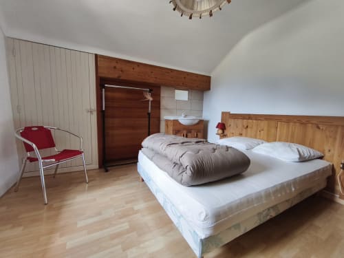 Ampia camera da letto nell'appartamento Chalet Coste Belle a Ceillac, con letto in legno, poltrona rossa e vista sulle montagne