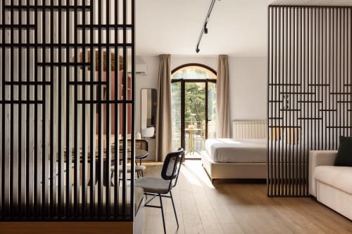 Interno moderno dell'appartamento Dimora Silva con divisori a doghe nere, pavimentazione in legno, letto, scrivania e portale ad arco