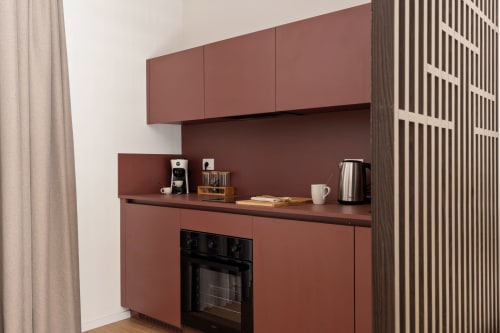 Angolo cottura moderno a Dimora Silva Nature Suites con mobili bordeaux, forno integrato e caffettiera.