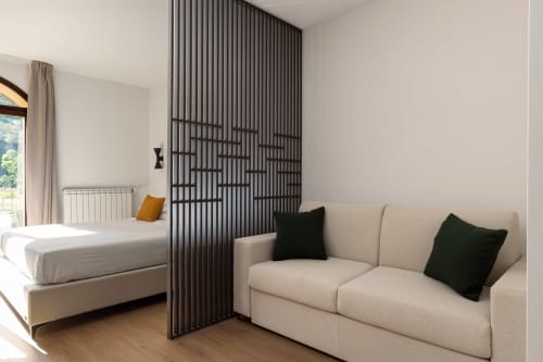 Monolocale moderno a Dimora Silva con letto, divano beige, parete divisoria nera e vista sulle montagne a San Martino delle Scale