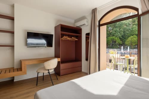 Camera moderna a Dimora Silva Nature Suites con vista montagna, scrivania in legno, TV e terrazza con vista sugli alberi
