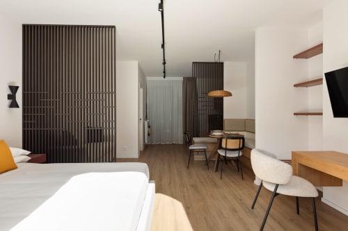 Moderno monolocale a Dimora Silva Nature Suites con letto, zona living, cucina e divisorio in legno scuro a San Martino