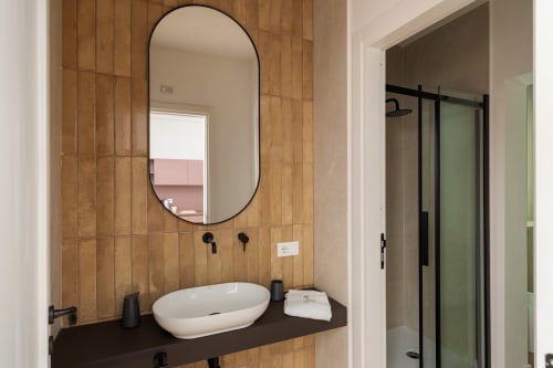 Elegante mobile bagno con specchio ovale e rubinetteria nera presso Dimora Silva Nature Suites, San Martino delle Scale