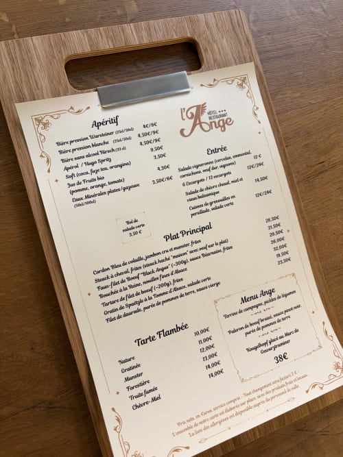 Menu du restaurant L'Ange à Niedermorschwihr affiché sur un presse-papiers en bois avec apéritifs, entrées et plats principaux