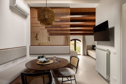 Suite moderna a Dimora Silva Nature Suites con divisori in legno, tavolo rotondo, TV e vista sulle montagne a San Martino