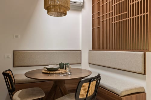 Zona pranzo moderna a Dimora Silva 7 con tavolo rotondo, panche imbottite, lampada a sospensione intrecciata e parete in doghe di legno