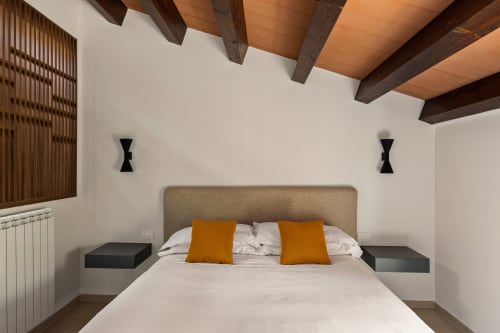 Camera moderna a Dimora Silva Nature Suites con travi in legno a vista, testata imbottita beige, biancheria bianca e