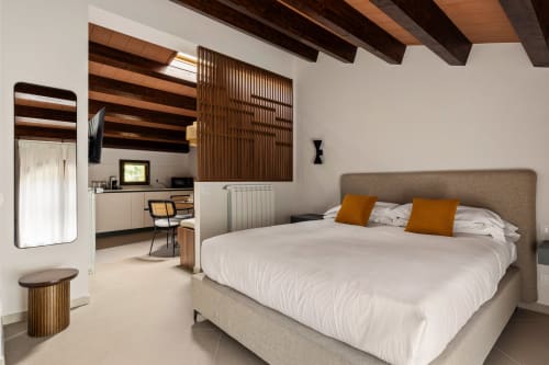 Camera moderna presso Dimora Silva Nature Suites con letto rivestito in grigio, biancheria bianca, travi in legno, angolo cottura e vista montagna