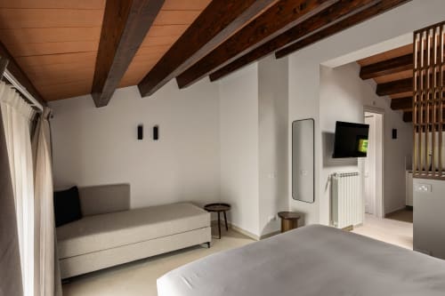 Camera moderna a Dimora Silva Nature Suites con travi in legno a vista, pareti bianche, letto, divano, TV e vista montagna a San