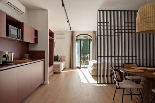 Cucina e zona pranzo moderna con mobili rosa, tavolo in legno e vista sulle montagne presso Dimora Silva Nature Suites