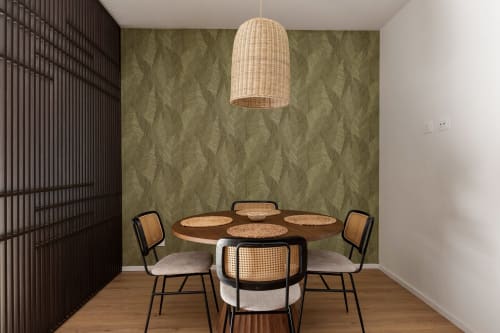 Sala da pranzo moderna a Dimora Silva 8 con tavolo rotondo in legno, sedie in rattan, lampada a sospensione intrecciata e carta da parati con motivi di ulivo