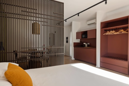 Camera moderna a Dimora Silva Nature Suites con divisorio in legno, elementi in terracotta, letto bianco e vista montagna