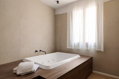 Bagno moderno a Dimora Silva 8 a San Martino delle Scale con vasca idromassaggio bianca, platform in legno scuro, asciugamani bianchi e
