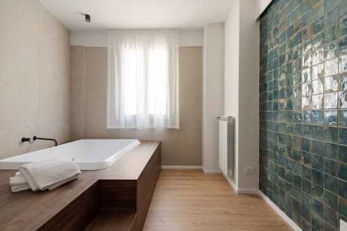 Bagno moderno con vasca bianca, vanità in legno, parete in piastrelle verdi e finestra alle Dimora Silva Nature Suites, San Martino