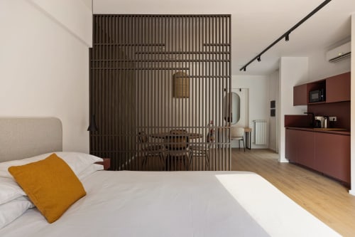 Camera moderna a Dimora Silva 8 con letto, cuscino senape, divisorio in legno e zona cucina a San Martino delle Scale