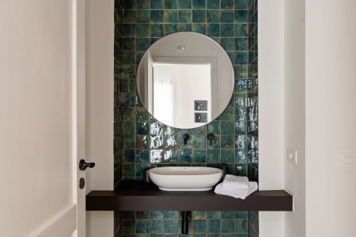 Moderno lavabo del bagno con bacinella ovale bianca, specchio circolare e parete rivestita in piastrelle verdi presso Dimora Silva Nature Suites, San Martino