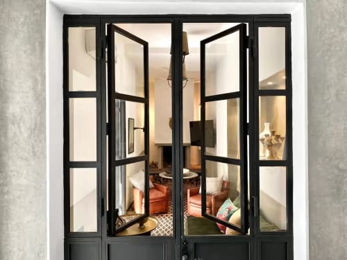 Portes-fenêtres noires ouvrant sur un élégant salon du Riad 191, Marrakech, avec éclairage chaleureux et décoration traditionnelle