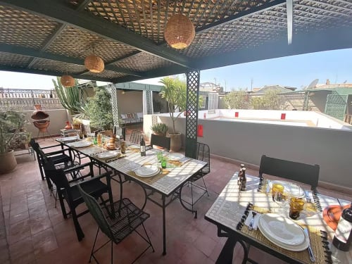 Terrasse panoramique du Riad 191 à Marrakech avec tables de restaurant, luminaires suspendus tissés et vue sur la ville