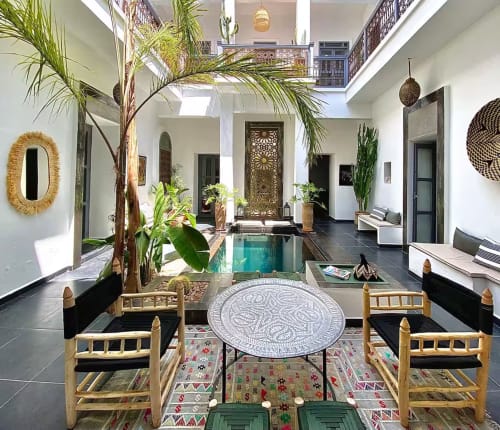Cour du Riad 191 à Marrakech avec piscine turquoise, chaises en bois traditionnel, palmiers et portes ornementales.