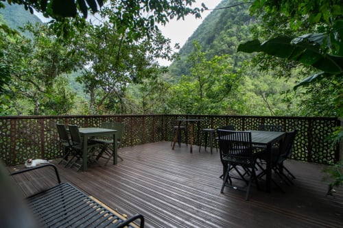 Terrasse en bois du Gîte Eden du randonneur avec vue sur les montagnes, tables de repas et végétation tropicale luxuriante