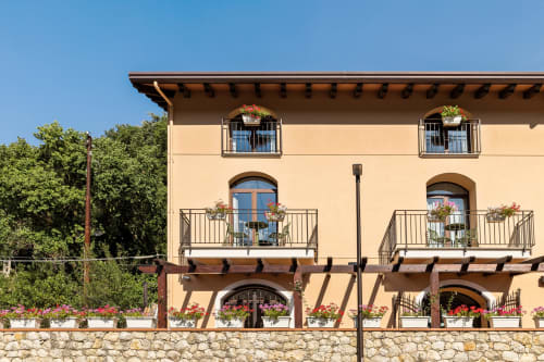 Esterno della Dimora Silva Nature Suites a San Martino delle Scale con facciata color crema, travi in legno, base in pietra e fiori