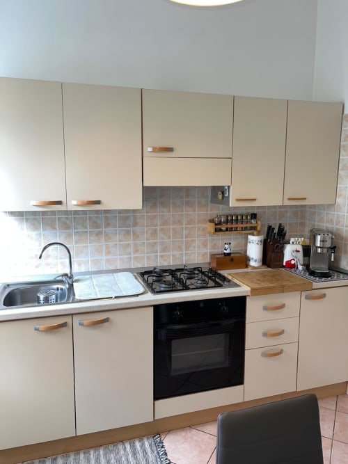 Cucina moderna nell'appartamento Orchidea di MiSaNi Apartments, Novara, con mobili color panna, piano cottura a gas e rivestimento in piastrelle
