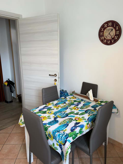 Zona pranzo dell'appartamento Orchidea presso MiSaNi Apartments, Novara con tavolo, sedie nere e biancheria colorata