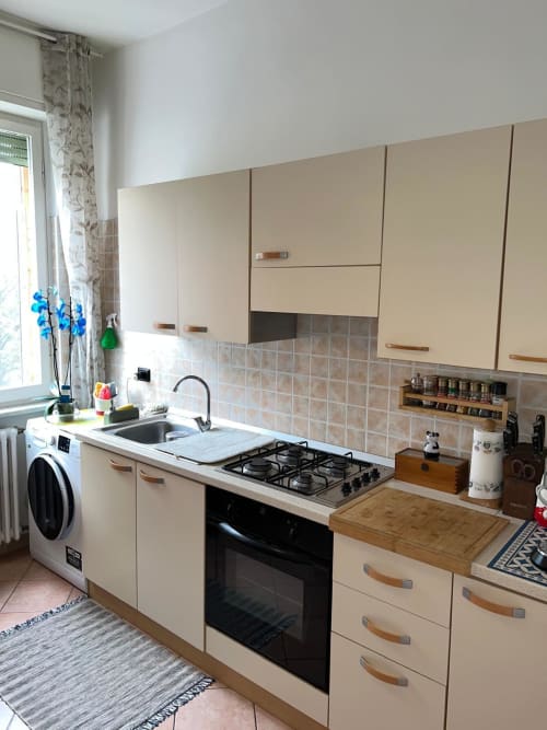 Cucina moderna dell'appartamento Orchidea a MiSaNi, Novara con mobili color crema, fornello a gas e piano di lavoro bianco