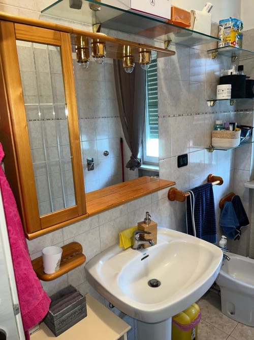 Bagno moderno dell'appartamento Orchidea presso MiSaNi Apartments, Novara con lavabo bianco a piedistallo, specchio in legno e vetro