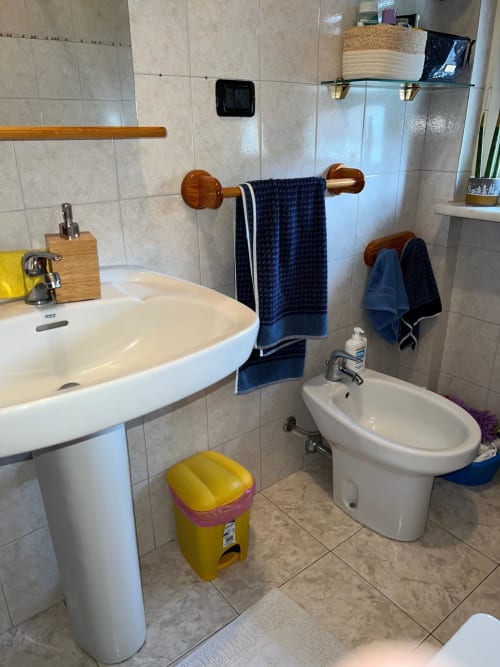 Bagno moderno negli Apartments MiSaNi Orchidea con lavabo bianco, bidet, portasciugamani e pareti piastrellate