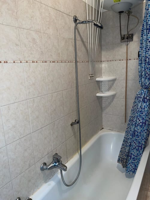 Bagno con vasca bianca, doccia e tenda a mosaico blu presso gli Appartamenti MiSaNi, Novara