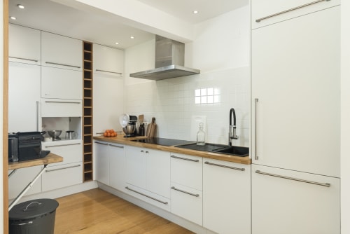 Modern kitchen in PHILL villa at RB Algarve with white cabinetry, black countertop, stainless steel appliances and wooden