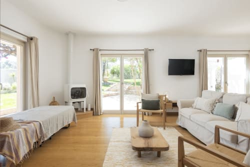Spacious villa living area at RB Algarve with wood floors, cream sofa, fireplace, and pool view through glass doors
