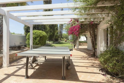 Ping-pong table under white pergola at RB Algarve villa in Boliqueime, Portugal, with gardens and magenta flowers