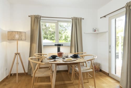 Modern dining area at RB Algarve villa with wooden table, wishbone chairs, and garden views through large windows with beige