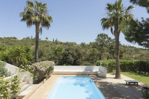 Private pool at RB Algarve villa in Boliqueime, Portugal, surrounded by palm trees and lush gardens with countryside views