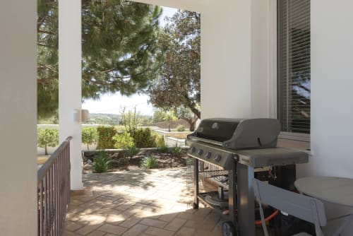 Modern patio at RB Algarve villa with gas grill, lounge seating, and scenic views of gardens and hills in Boliqueime,
