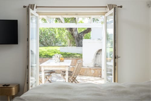 Bedroom view overlooking patio with wooden table and chairs, garden with mature tree at RB Algarve villa in Boliqueime,