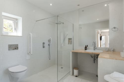 Modern bathroom at RB Algarve villa with walk-in shower, double sink vanity, and white tile design