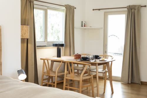 Modern villa dining area at RB Algarve with wooden table, chairs, and natural light from French doors overlooking pool area