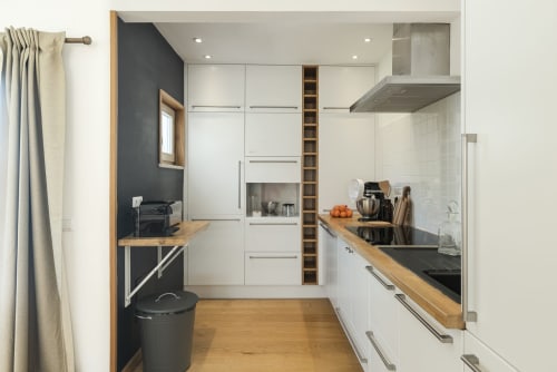 Modern kitchen at RB Algarve villa with white cabinetry, dark accent wall, wooden counters, stainless appliances
