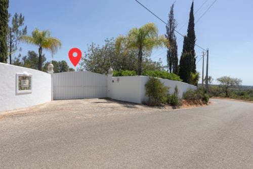 White villa entrance with red location pin at RB Algarve, Boliqueime, Portugal, featuring gated driveway and Mediterranean