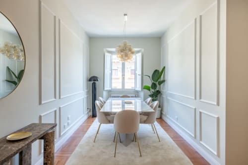 Elegante sala da pranzo presso Lovely Rome Apartments con pareti rivestite di bianco, pavimenti in legno, lampada a sospensione moderna e ampia