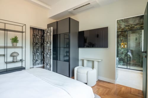 Camera da letto moderna in appartamento romano con letto bianco, guardaroba nero, doccia in vetro, pavimento a spina di pesce e vista città