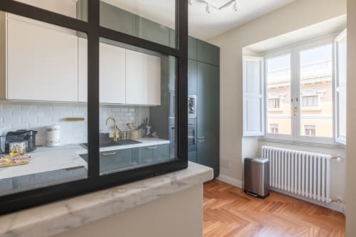 Cucina moderna con armadiature scure, ripiani bianchi e isola in marmo in appartamento romano con vista sulla città